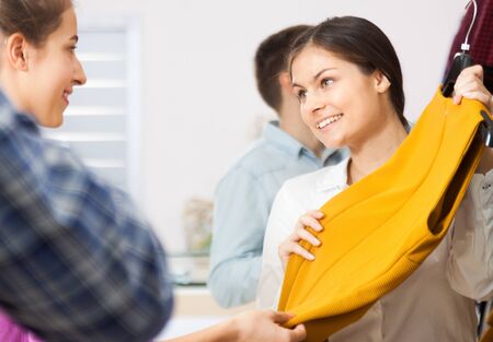 Happy salesman shows a young woman yellow dressの写真素材