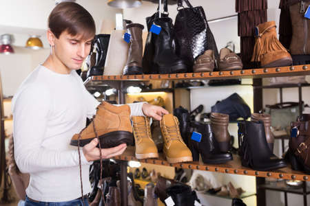 Happy man choosing winter shoes in a shoe shopの写真素材