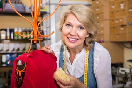 professional mature woman sewing gown in clothing workshopの写真素材