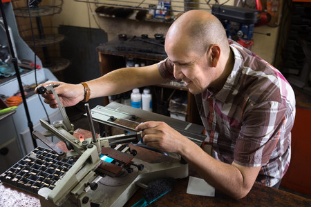 Mature specialist making mailbox plate on machine