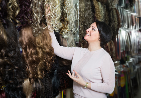 smiling middle aged brunette woman stylish wig in storeの写真素材