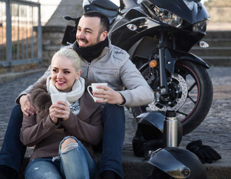 Young family couple relaxing with coffee near motor bikeの写真素材