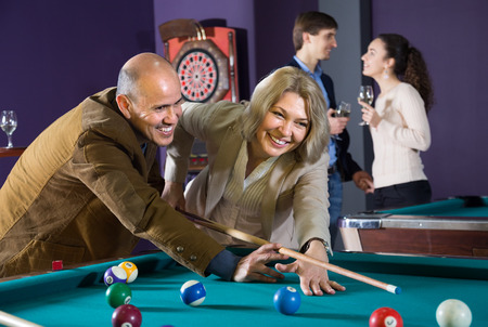 happy mature couple playing a game of billiards. young couple drinking wineの写真素材