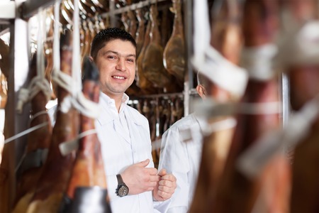 butcher hanging wurst and jamon joints at meat factoryの写真素材