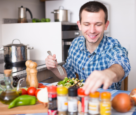 guy preparing salad in kitchen at homeの写真素材