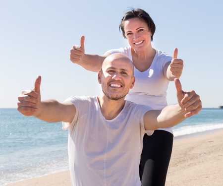 happy man and a middle-aged woman in white T-shirt sitting on the beachの写真素材