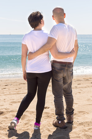 elderly man hugs a woman on the beach. view from the back on leaveの写真素材