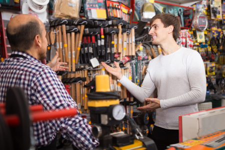 Smiling salesman showing different tools and instruments in supermarketの写真素材