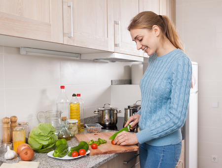 Happy young householder learning new recipe of vegetables at homeの写真素材