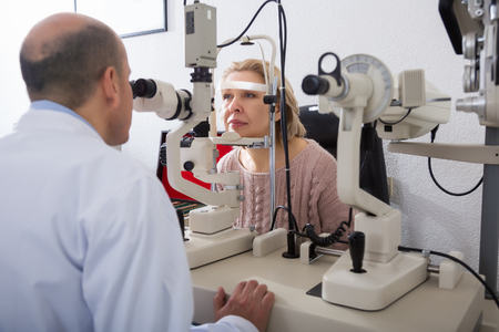 Portrait of elderly woman who is explores eyesight with aid of slit lamp in clinicの写真素材