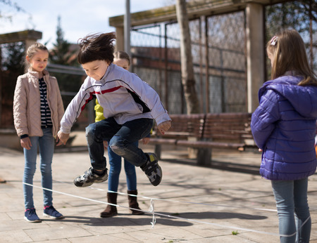active children games. Boy jumps over the rope in park in autumnの写真素材