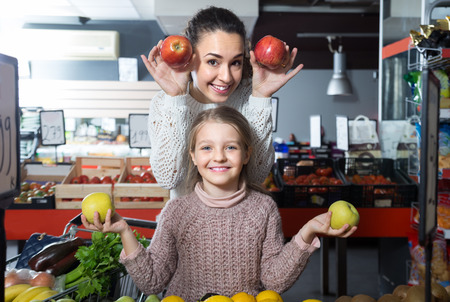 mother and  posinive daughter buying apples in shopの写真素材