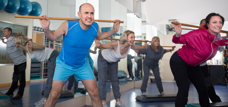 positive elderly exercise with gymnastic sticks in modern gymの写真素材