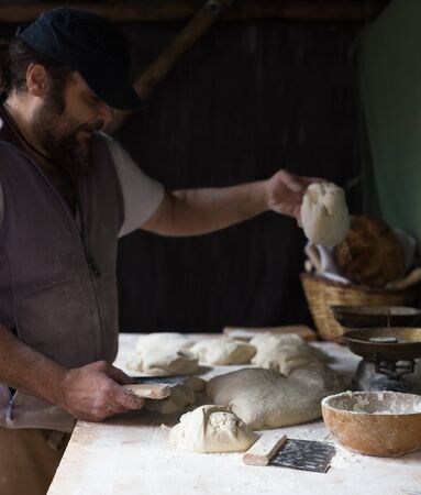 Male baker razdelyvet dough for baking bread.
