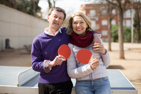 portrait of Happy mature couple with rackets for table tennis outdoorsの写真素材