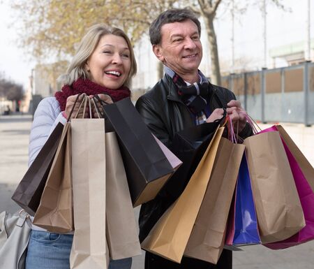 Happy mature couple with shopping bags in autumn dayの写真素材