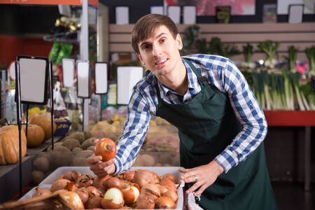 Portrait of pretty young man working in grocery and smilingの写真素材