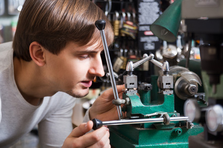 Ordinary handyman making copies of door keys in locksmithの写真素材