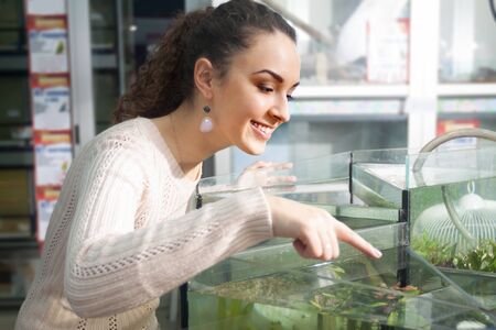 Portrait of young brunette female selecting algae in petshopの写真素材