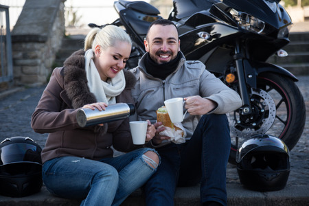 Young family couple posing near motor bike with coffeeの写真素材