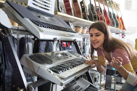 Teenage girl selecting synthesizer in music instruments shopの写真素材
