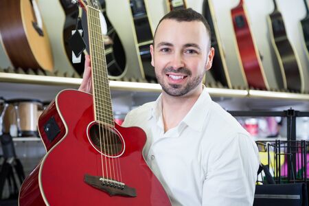 Male buyer choosing guitar in music storeの写真素材