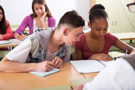 ordinary European student write off from notebook Aframerican studentgirl in classroomの写真素材
