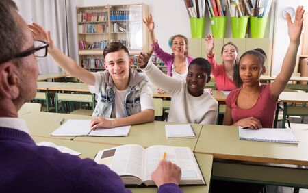 smiling students pull hands on lesson at schoolの写真素材
