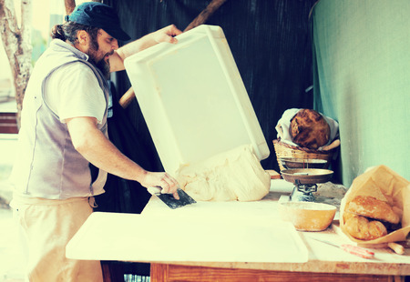 Male baker razdelyvet dough for baking breadの写真素材