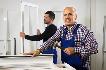 Two careful workmen work at PVC windows factoryの写真素材