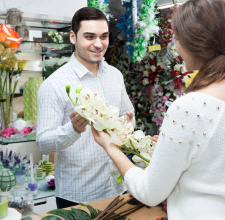 Young female seller offering flowers maleの写真素材
