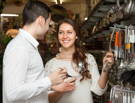 Young couple chooses cooking utensils at shopの写真素材