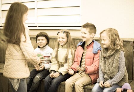 ordinary boys and girls play together with Ball in school yard in autumn