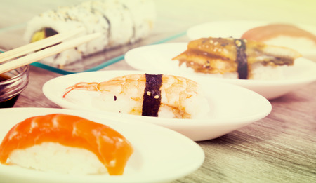 four kinds Nigirisushi on oval saucers and Uramaki. focus on ebiの写真素材