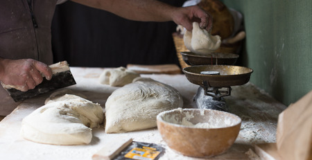 Male baker razdelyvet dough for baking bread