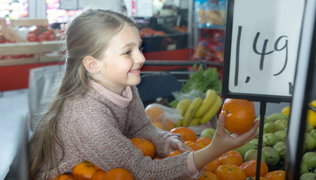smiling little girl buying mandarins in shopの写真素材