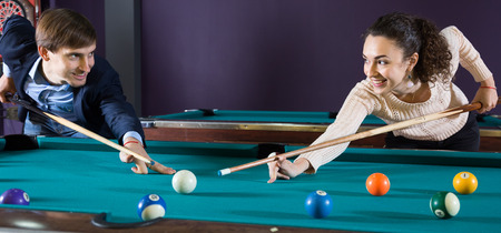 smiling young couple playing pool looking at each otherの写真素材