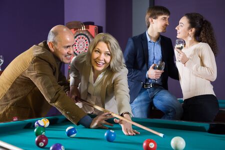 smiling elderly couple learns to play billiards. focus on mature womanの写真素材