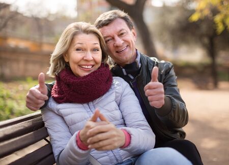 Mature family couple on a bench in the park in autumn dayの写真素材