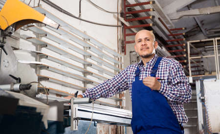 middle-aged worker in coveralls posing in workshopの写真素材
