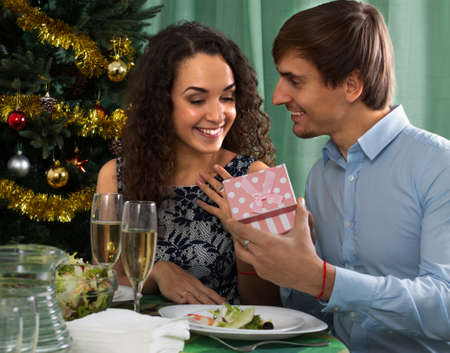 Man giving surprise present to woman during dinner in homeの写真素材