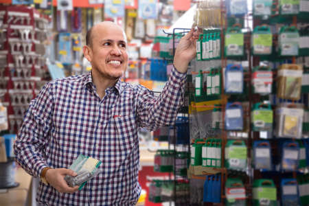 Ordinary elderly man choosing tooking in household storeの写真素材