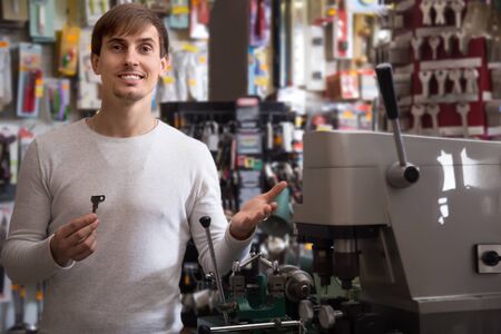 Friendly smiling professional with different types of keys in locksmithの写真素材