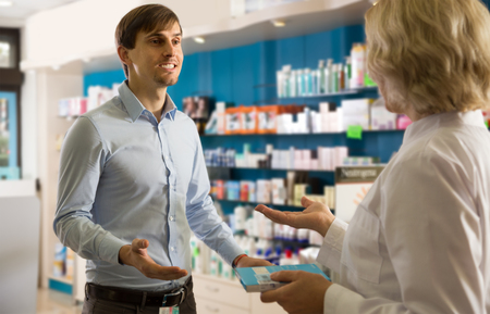 Young interested man near counter in  drugstoreの写真素材