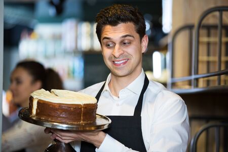 Young man confectioner holding delicious cakeの写真素材