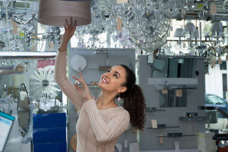 Ordinary young brunet woman doing shopping in lighting storeの写真素材