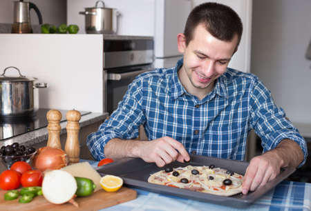 Young man preparing pizza in the kitchenの写真素材