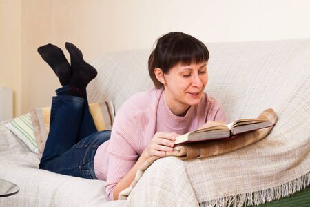 Woman reading a book at homeの写真素材