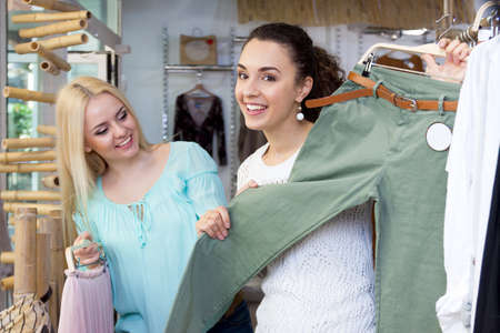 Pretty female customers choosing new garment in fashion storeの写真素材