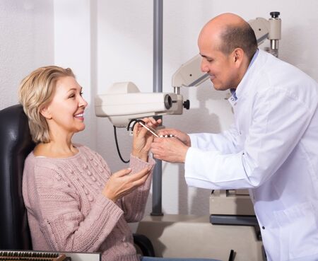 Mature optician examinating eyesight with aid of slit lampの写真素材